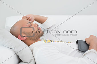 Businessman sleeping on sofa with digital tablet at home