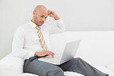 Businessman using laptop on sofa at home