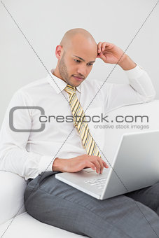 Businessman using laptop on sofa at home