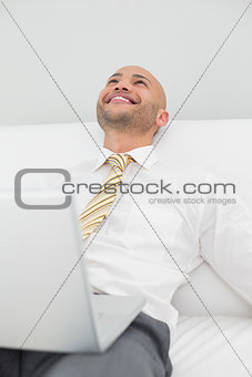 Businessman looking up while using laptop