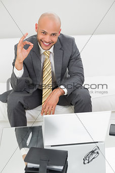 Businessman gesturing okay sign with laptop at home
