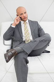 Businessman using cellphone on sofa at home