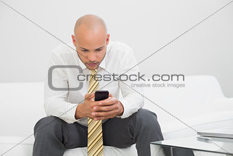 Serious young businessman text messaging