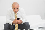 Serious elegant young businessman text messaging