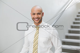 Smiling elegant businessman standing against staircase