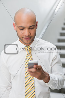 Businessman text messaging against staircase