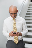 Smiling businessman text messaging in office