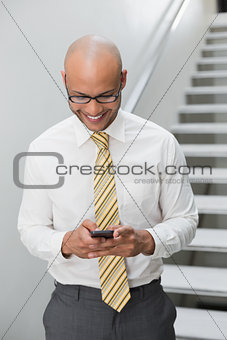 Smiling businessman text messaging in office