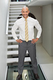 Smiling businessman standing against staircase
