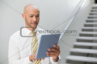 Serious elegant young businessman using digital tablet