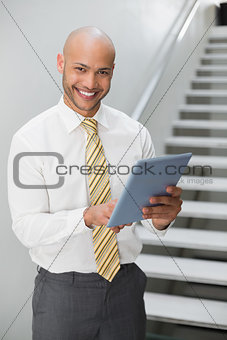 Smiling elegant young businessman using digital tablet