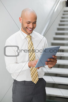 Smiling elegant young businessman using digital tablet