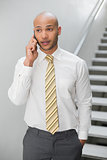 Serious elegant young businessman using cellphone