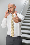 Businessman using cellphone and gesturing thumbs up