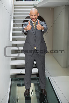 Elegant businessman gesturing thumbs up against staircase