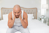 Bald man suffering from headache in bed
