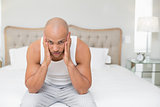 Portrait of bald man suffering from headache in bed
