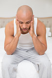 Bald man suffering from headache in bed