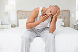 Bald man sitting and yawning in bed