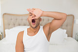 Young man yawning in bed