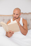 Relaxed bald man reading book in bed