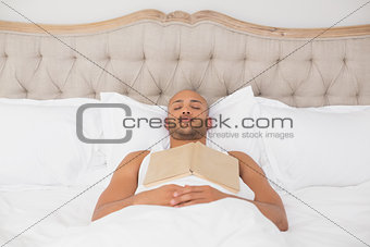 Relaxed man with book lying in bed