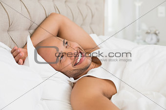 Smiling young bald man resting in bed