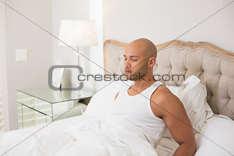 Relaxed young bald man with eyes closed in bed
