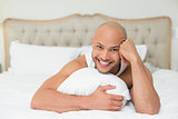 Smiling casual bald young man lying in bed