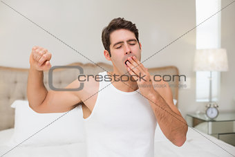 Man waking up in bed and stretching his arms