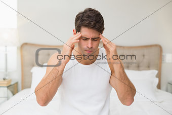 Young man suffering from headache in bed