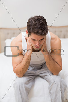 Thoughtful young man sitting in bed