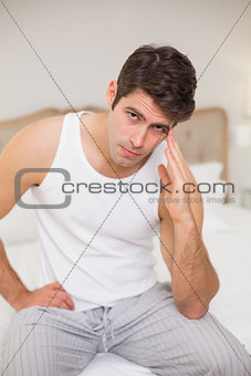 Portrait of man suffering from headache in bed