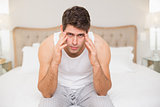 Portrait of man suffering from headache in bed