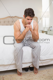Full length of thoughtful man sitting in bed