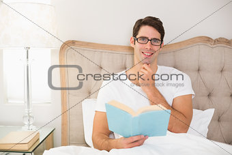 Portrait of relaxed man reading book in bed