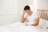 Young man suffering from headache in bed