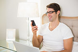 Casual smiling man text messaging in bed