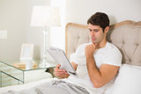 Casual man reading newspaper in bed
