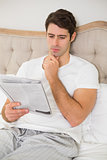 Casual man reading newspaper in bed