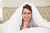 Close up portrait of a smiling man resting in bed