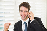 Portrait of smiling businessman using mobile phone while clenching fist