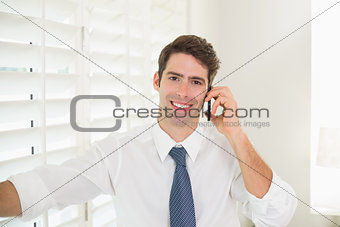 Smiling businessman using mobile phone in office