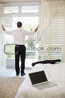 Businessman looking through window at a hotel bedroom