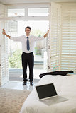 Smiling businessman by window at a hotel bedroom