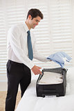 Smiling businessman unpacking luggage at a hotel bedroom