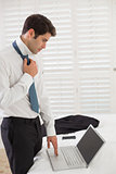 Businessman wearing tie while using laptop at a hotel room