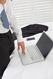 Mid section of a businessman using laptop at hotel room