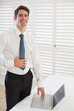 Smiling businessman using laptop at hotel room
