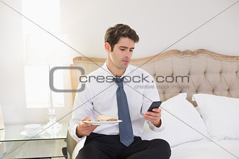 Well dressed man text messaging in bed at home